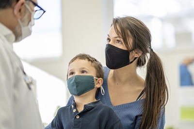 mother and toddler wearing face masks in doctors office