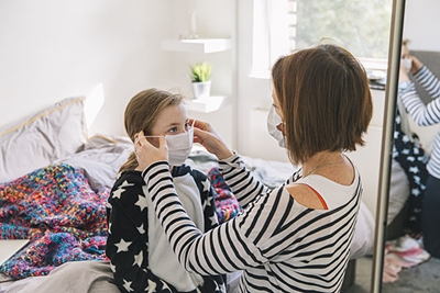 mother fitting face mask on 10 year old girl